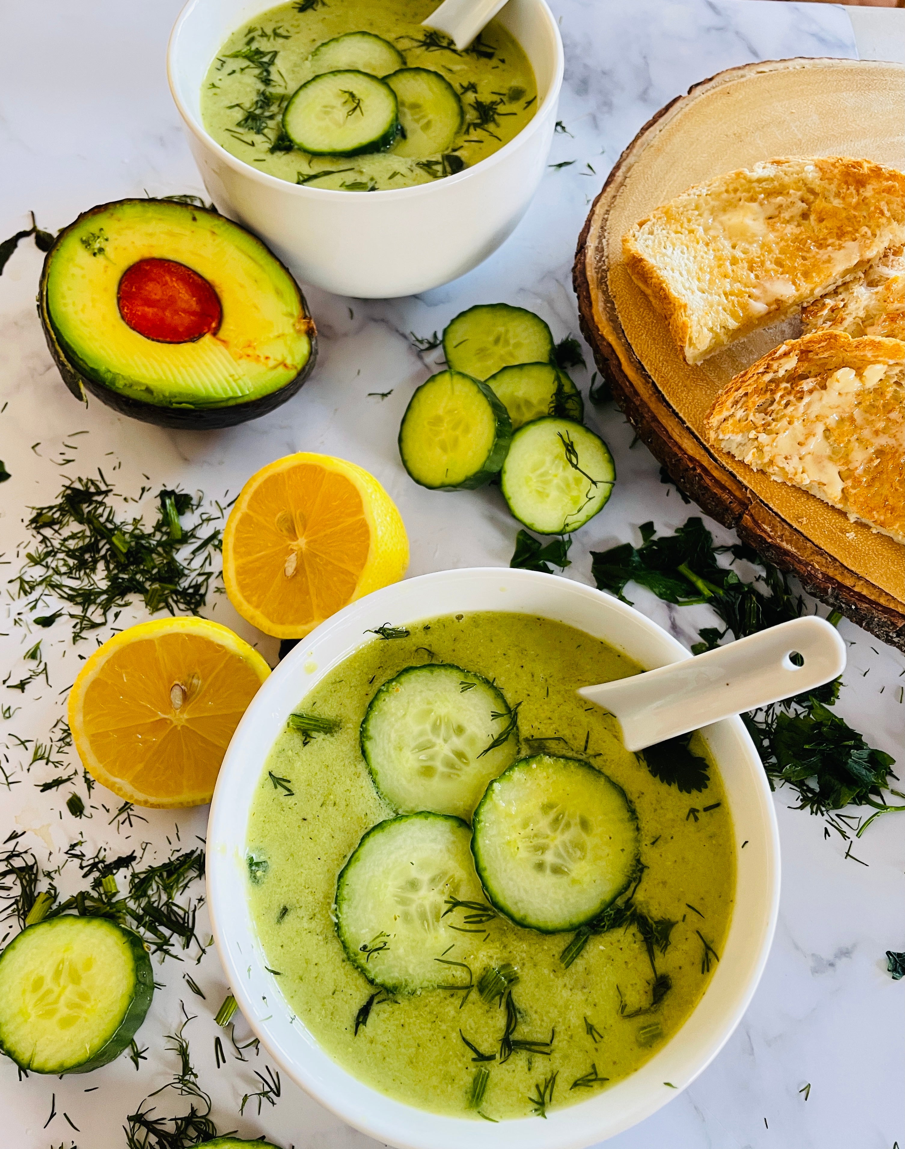 Cucumber Avocado soup with raw ingredients around it 